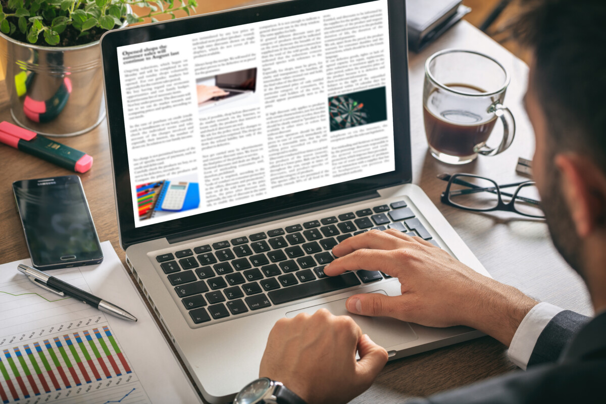 Man working on a laptop - news on the screen