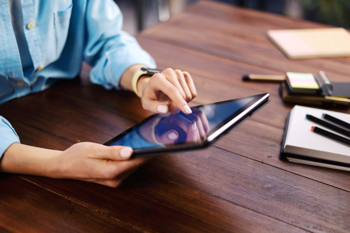 Woman pointing on digital tablet screen, chatting in social networks, meeting website, searching internet, sending sms, using text messenger or online banking. Close up of female hands holding device